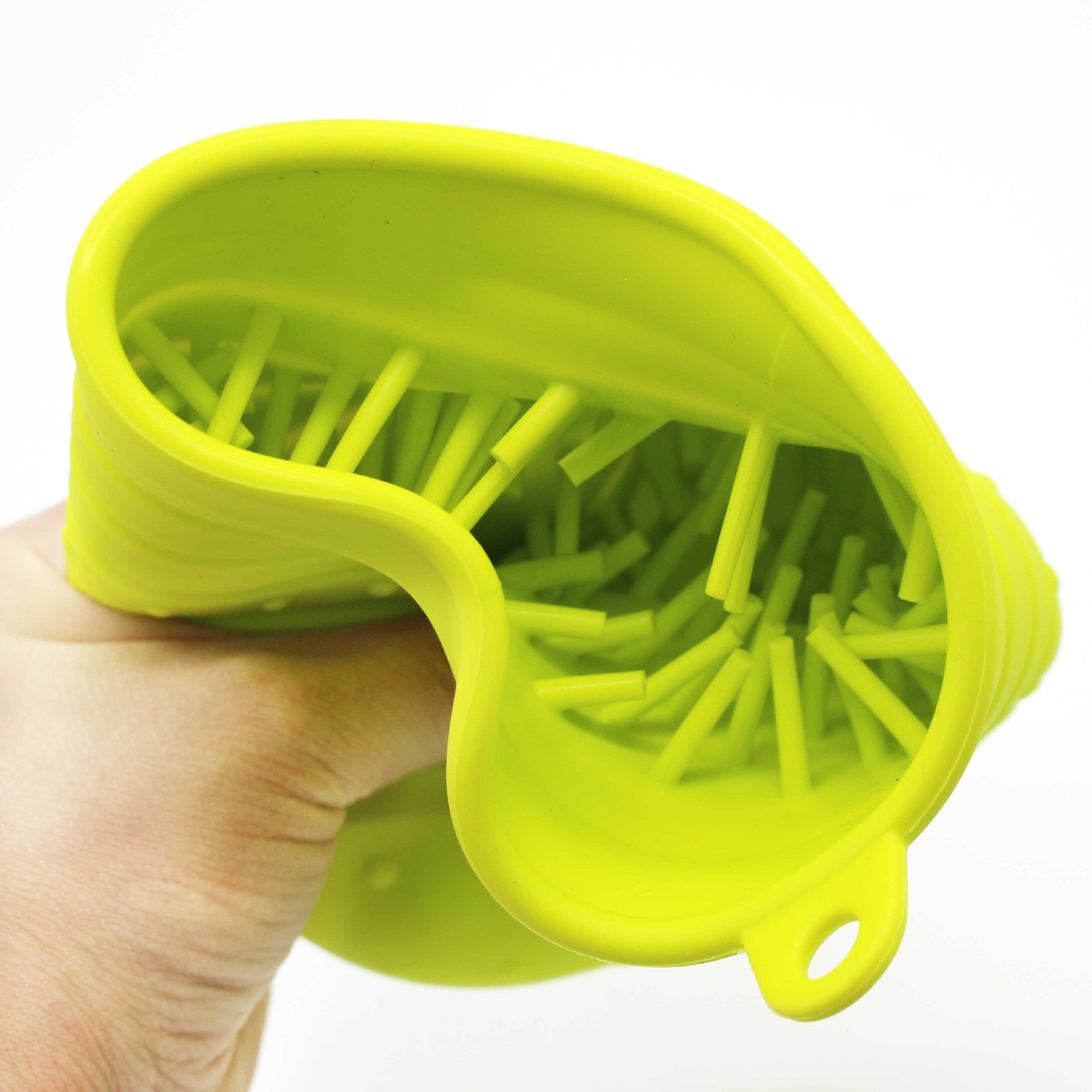 Hand holding a green silicone tool with small green sticks inside on a white background